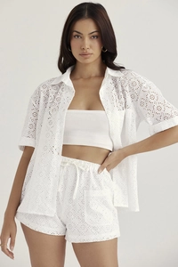 Detailed close-up of white broderie anglaise embroidery on a short sleeve shirt set