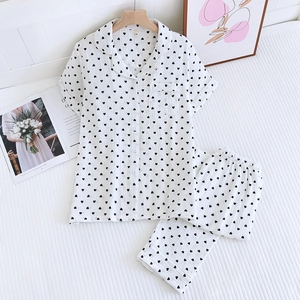 Vue détaillée du pyjama en coton blanc pour femme avec motif cœur noir sur literie rayée