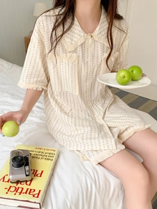 Detail of beige pajama set with fringe trim and dotted stripes on soft cotton fabric