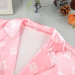 Detail of pink satin shirt collar with white letter prints and smooth fabric texture