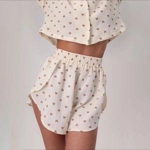 Close-up detail of cream pajama set featuring brown heart prints and seersucker texture