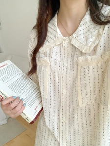 Detail of bohemian fringe collar and striped cotton fabric on beige pajama top