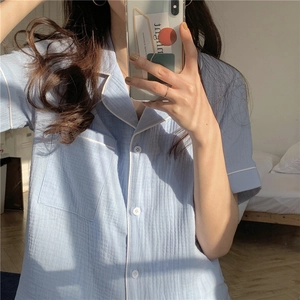 Detail of light blue short-sleeve gauze pajama set featuring white piping and chest pocket
