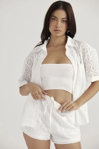 Detailed view of white hollow lace embroidery texture on a short-sleeve shirt and shorts set
