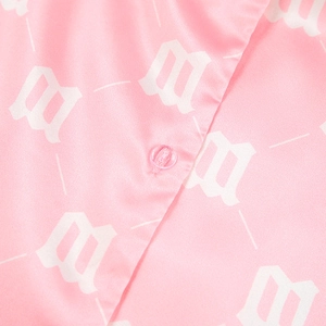 Detail of pink satin shirt featuring white gothic M letter print and a matching round button