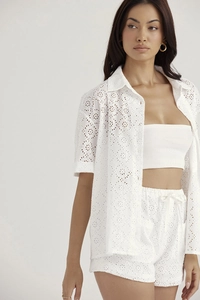 Detail of white Broderie Anglaise hollow-out lace texture on summer shirt and shorts set