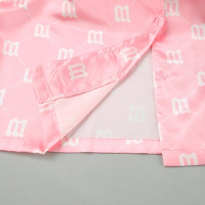 Close-up of pink satin shirt with white M-letter pattern and high-quality stitching
