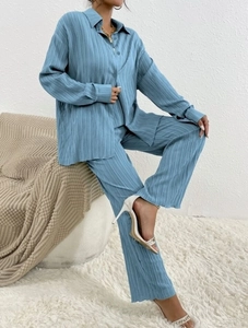 Detail of blue pleated long-sleeve shirt and matching pants with soft texture fabric