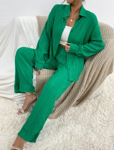 Detail of green pleated fabric texture on a long sleeve shirt and wide-leg pants set