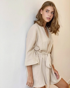 Detail of light beige crepe gauze bathrobe with kimono neckline and waist tie closure
