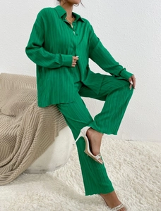 Detail showing grass green pleated fabric texture on a long sleeve shirt and wide-leg trousers