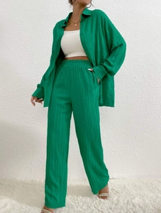 Bright green pleated two-piece set featuring oversized shirt and wide-leg trousers