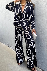 Detail view of smooth satin pajamas set with white abstract prints on black fabric