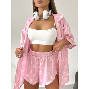 Pink satin lounge set featuring oversized printed shirt and shorts with M-pattern