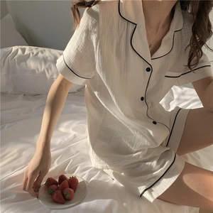 Close-up of a cream summer gauze pajama set with black piping and button-down detail