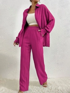 Detail of rose red plissé pleated shirt and high waist wide leg trousers two-piece set