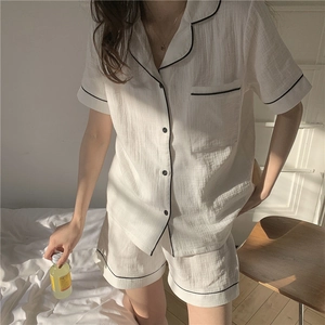 Detail of white cotton pajamas with black piping contrast on short sleeve shirt and shorts