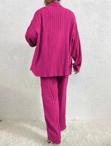 Back view of magenta pleated two-piece set featuring long-sleeved shirt and wide-leg trousers