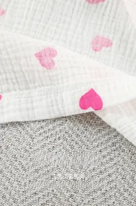Makroaufnahme von atmungsaktivem weißem Baumwollmull mit rosa Herzprint und feiner Naht