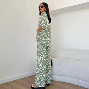Dettaglio dei pantaloni in raso con stampa zebra verde e camicia a maniche corte