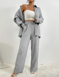 Detail of grey pleated fabric texture on relaxed fit long sleeve shirt and wide leg trousers
