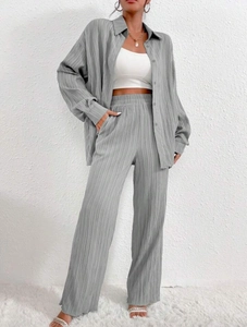 Detail view of sage green pleated fabric texture on a loose shirt and wide-leg pants