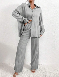 Detail of grey plissé fabric texture on women's oversize shirt and wide leg trousers set