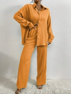 Detailed view of orange pleated fabric texture on relaxed oversized lounge set