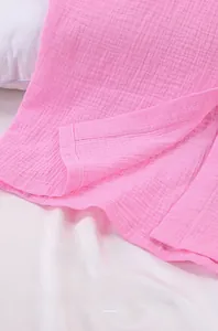 Macro shot of pink muslin cotton fabric detailing neat stitching and buttonhole