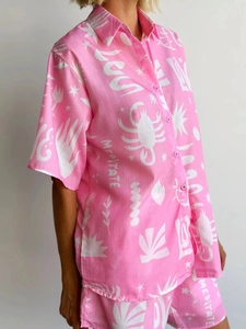 Detail of pink shorts set featuring white scorpion and meditate graphic prints