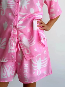 Detail of pink floral set showing linen texture and MEDITATE print on short sleeve shirt
