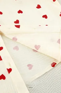 Détail du tissu en double gaze douce avec imprimé cœur et bords à volants délicats