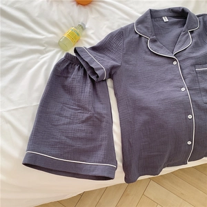 Detail view of dark grey cotton gauze pajamas with white piping and elastic waistband