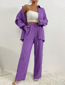 Detail of purple pleated fabric texture on a long-sleeve casual shirt and wide-leg trousers