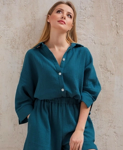 Detail view of teal cotton muslin long sleeve shirt with white resin button closure