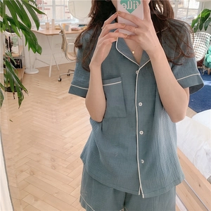 Detail of blue gauze pajama set with white piping and chest pocket in a cozy home setting