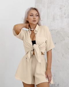 Detail showing beige crinkled cotton texture on loose shirt and high-waist shorts set
