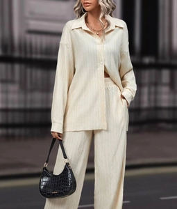 Detailed texture of beige pleated fabric on loose-fit long sleeve shirt and wide-leg trousers