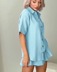 Detail of light blue crinkle cotton pajamas featuring natural wood buttons and soft texture