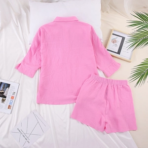 Flat lay of pink cotton crepe pajama set with button-down top and elastic waist shorts
