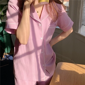 Detail of pink seersucker pajamas showing textured fabric, piping, and pearl buttons