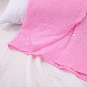 Detailed macro view of pink cotton crepe pajamas featuring natural shell buttons