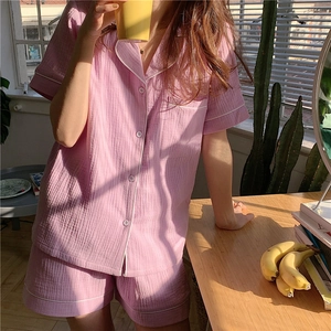 Close-up of pink gauze pajama set with white piping in warm natural sunlight