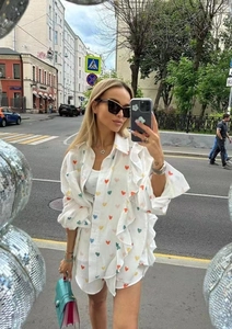 Detail of ruffled white linen loungewear with colorful heart print in street style