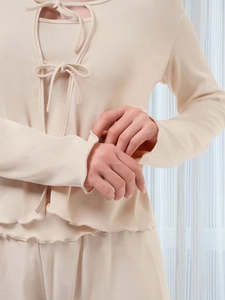 Dettaglio pigiama in maglia con chiusura a fiocco e delicati bordi a lattuga