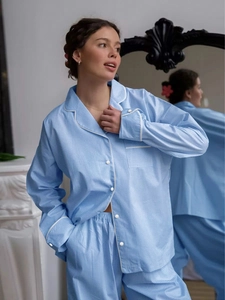 Close-up of light blue gingham pajama set with white piping and button-down details