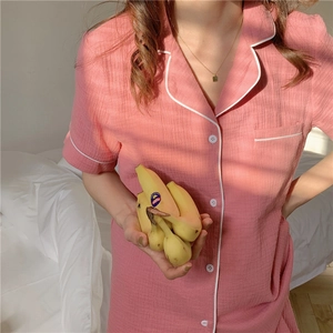 Detail of pink gauze pajama top with classic lapel, white piping, and textured fabric
