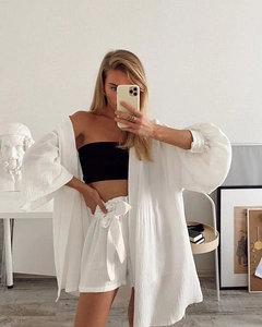 Detailaufnahme eines weißen Damen-Baumwoll-Cardigans mit schwarzem Crop-Top im Spiegel