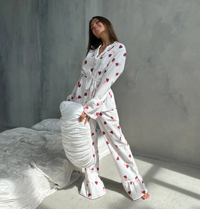 Detail of white cotton pajamas with red heart prints, drawstring waist, and ruffled hem