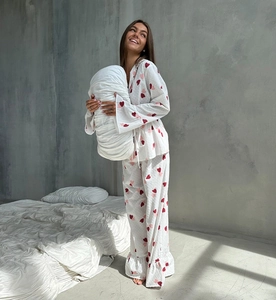 Detail of white cotton pajamas featuring red heart print and ruffled hems on trousers